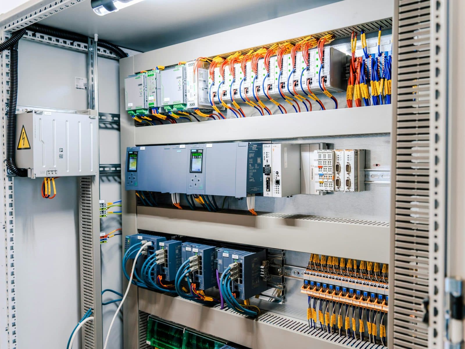 Open industrial control cabinet with controllers, network modules and wiring